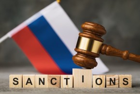 Russian flag, gavel hitting wooden letters with the word "Sanctions"