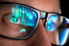 Data reflected from a screen onto a man's glasses.